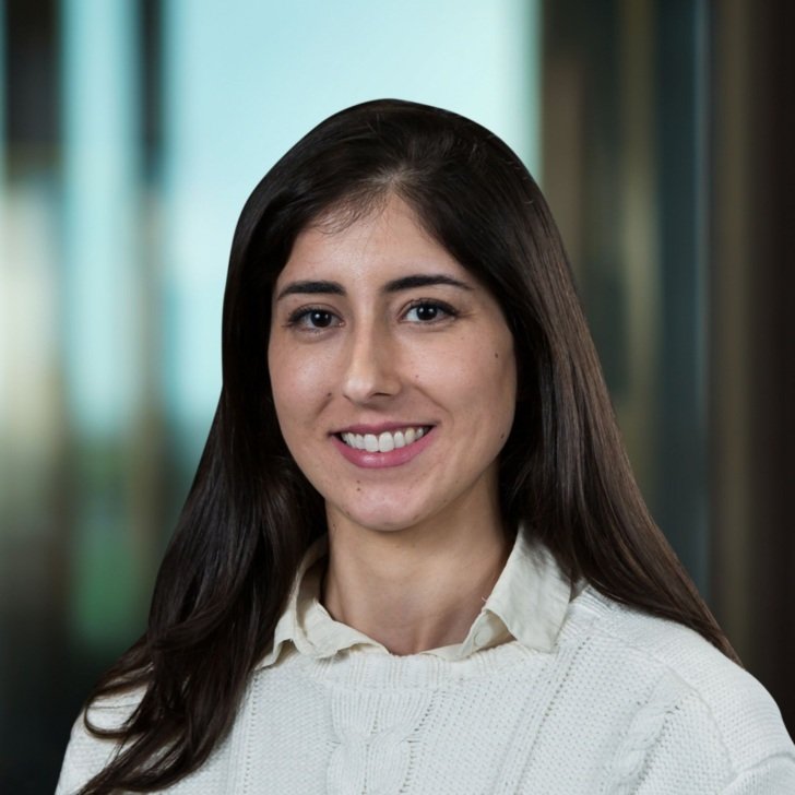 Woman with long dark hair wearing a white collared shirt and jumper