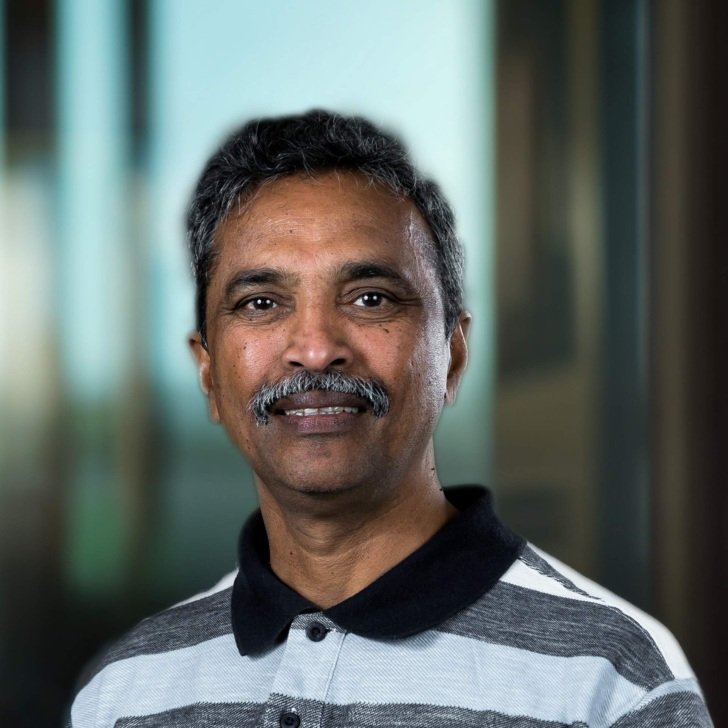 Man with dark hair and moustache wearing a white and grey striped tshirt