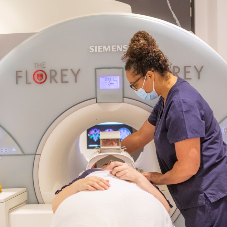 MRI radiographer assists patient into an MRI scanner