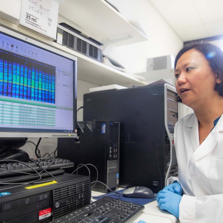 Female researcher looks at DNA sequence on a computer screen