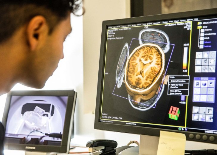 Male research radiographer examines an MRI scan in an MRI facility