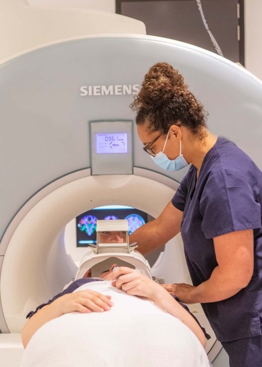 Research radiographer helps patient into MRI scanner