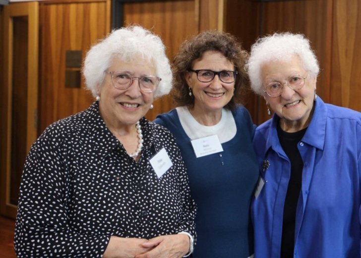 Two older women with short grey hair and glasses standing either side of Florey Bequests Manager. They are all looking at the camera and smiling.