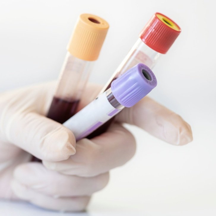 Close-up of researcher wearing white gloves and holding three test tubes