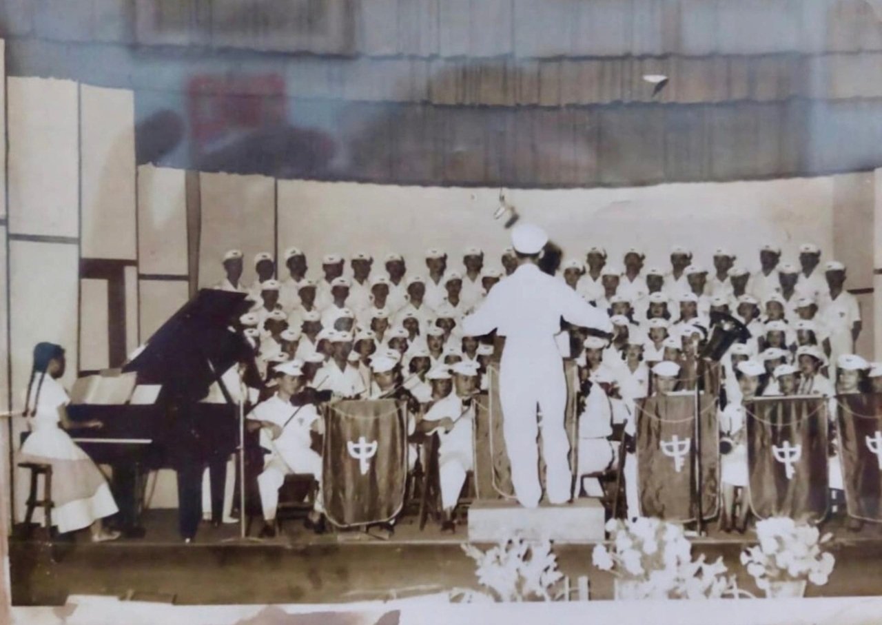 An old photo of Patricia's grandmother on the piano, accompanying her students in a choir orchestra