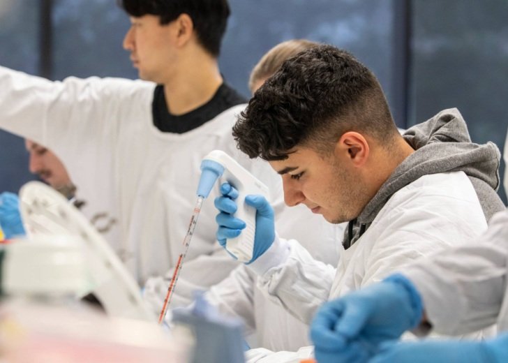 Male student in a white laboratory coat using a pipette in a Florey laboratory