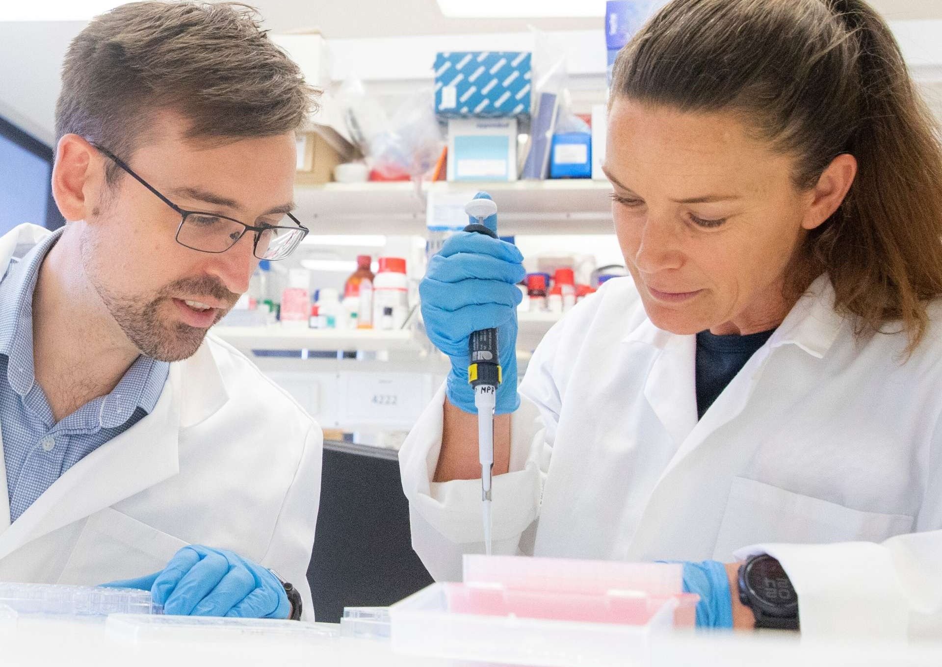 Man and woman in white laboratory coats examining samples in a Florey lab.