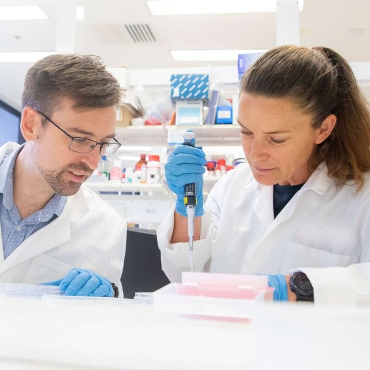 Man and woman in white laboratory coats examining samples in a Florey lab.