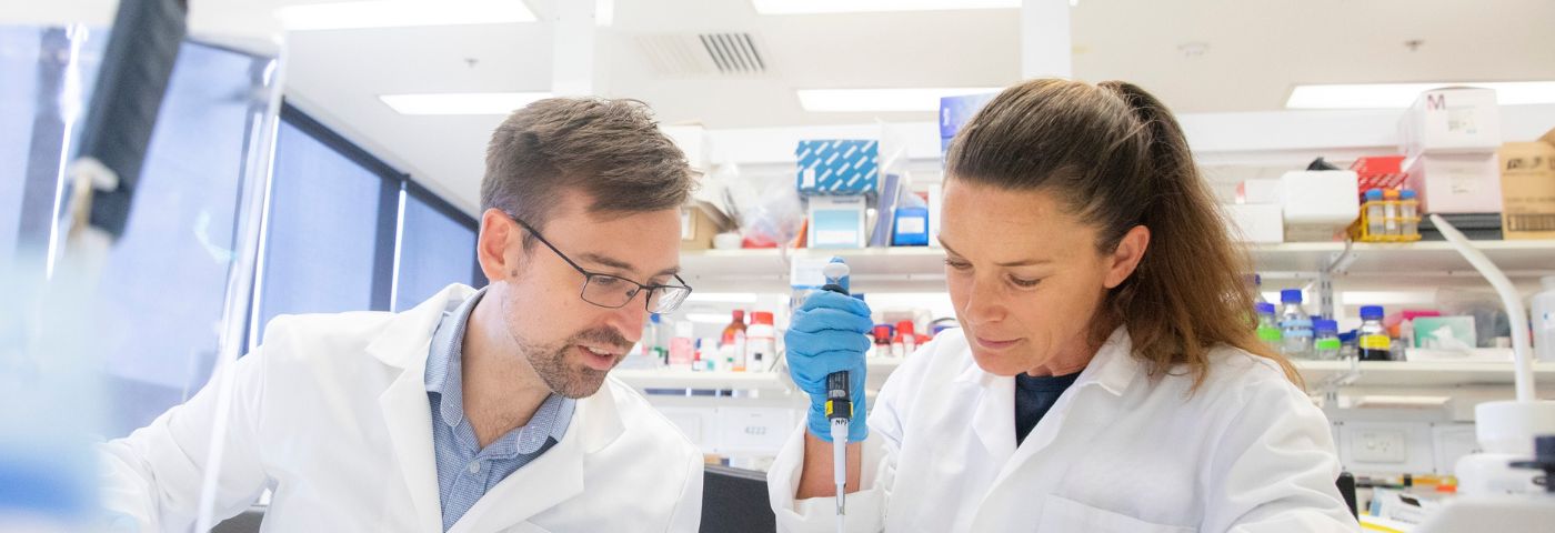 A man and woman wearing white laboratory coats working at a lab bench at The Florey