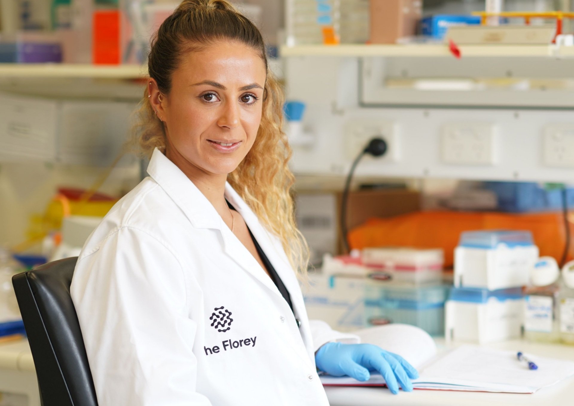 Scientist wearing lab coat rests hand on laboratory bench