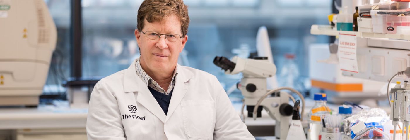 Man wearing lab coat sits in research laboratory