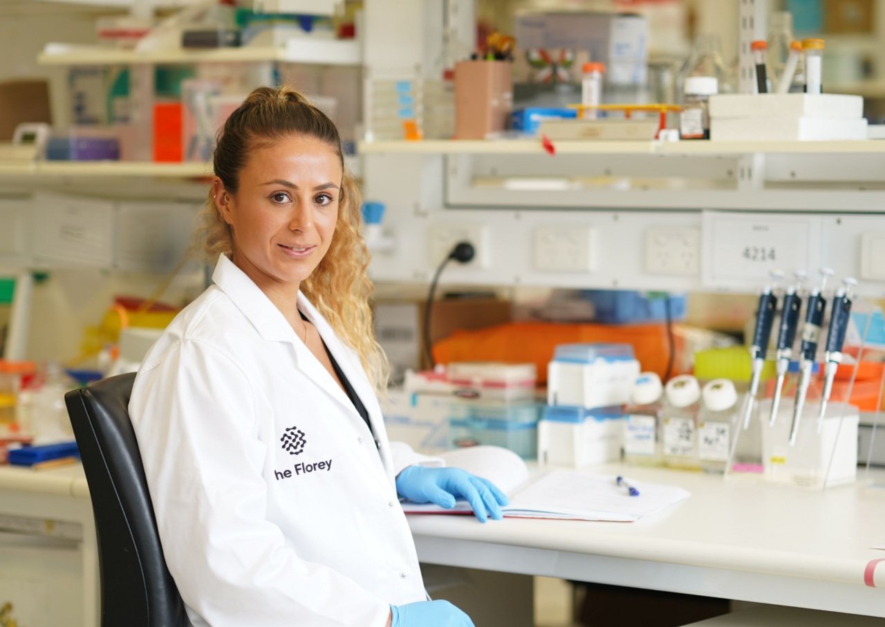 Scientist wearing lab coat sits at laboratory bench