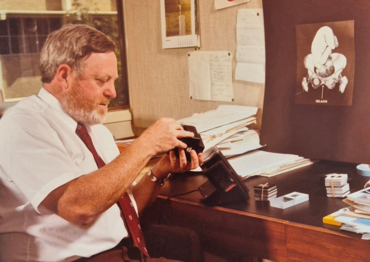 Man fixes piece of scientific equipment while sitting at a desk