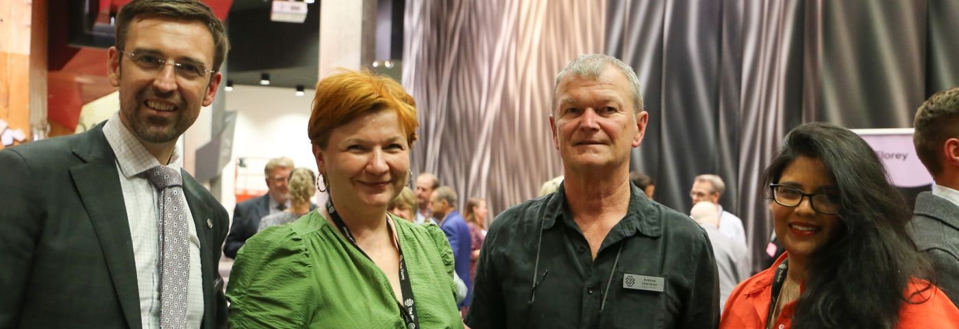 Four people smile while standing in Florey lobby