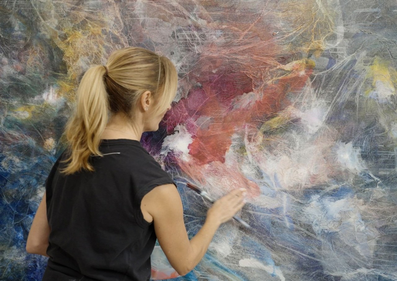 Woman paints colourful canvas