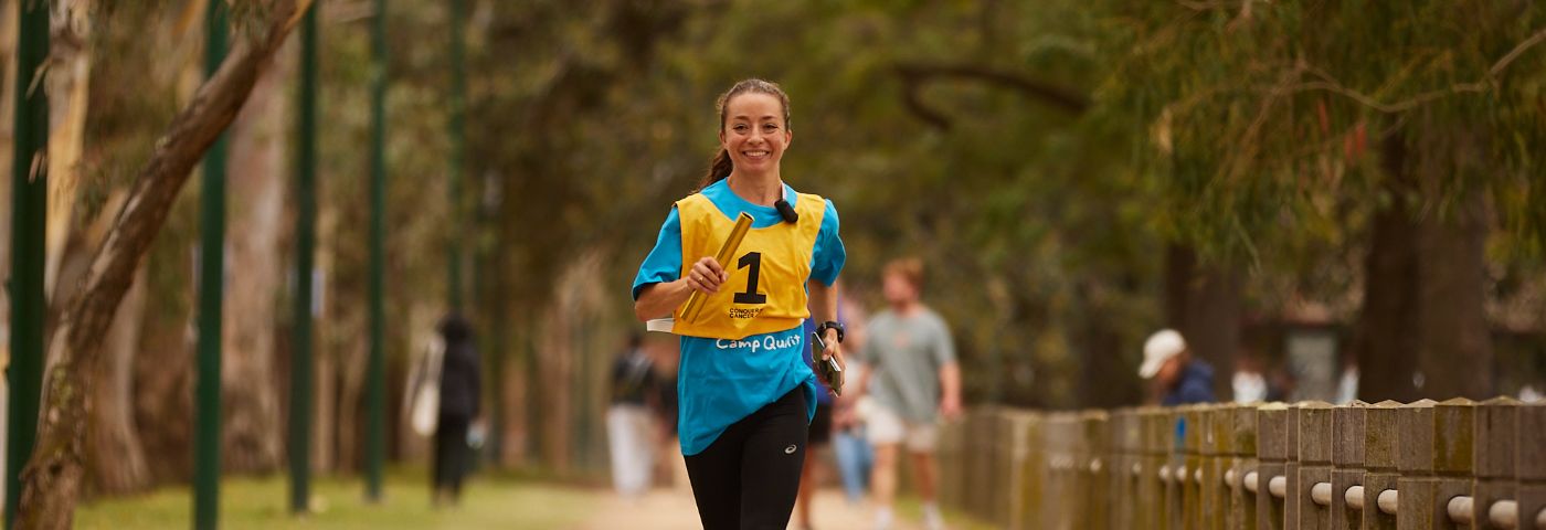 Woman smiling holding gold baton speed-walks around park