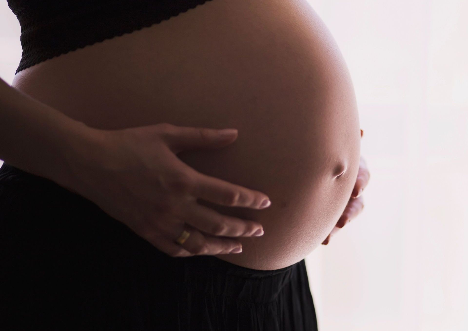 Woman holds pregnant belly