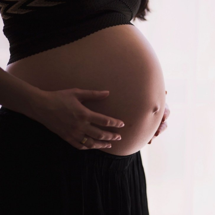 Woman holds pregnant belly