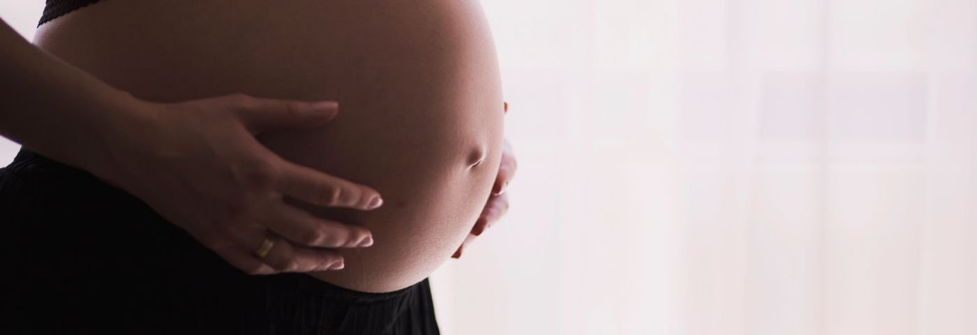Woman holds her pregnant belly