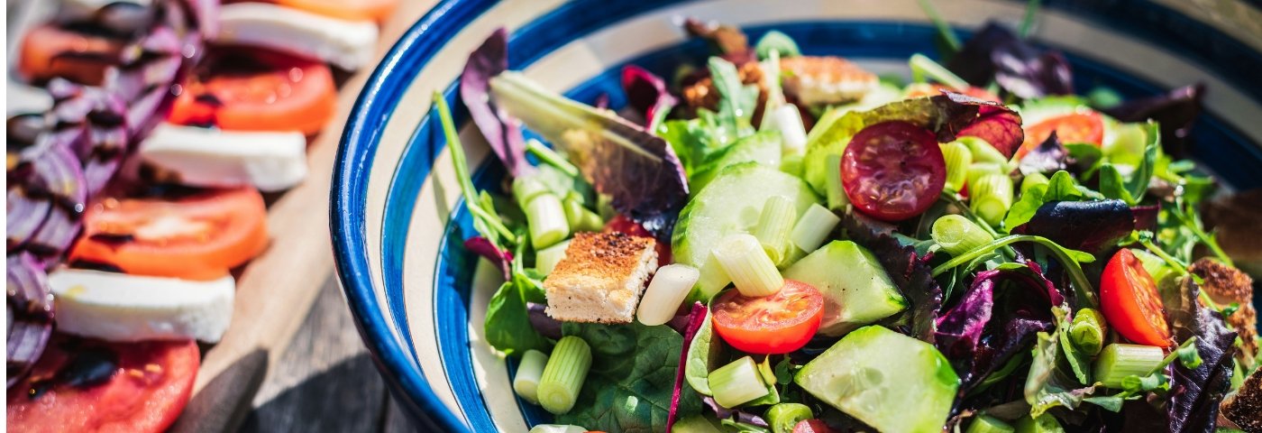Bowl of leafy green salad with tomatoes and cucumber