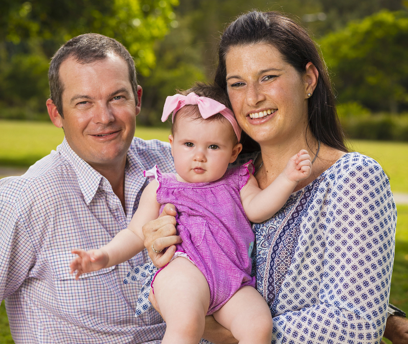 Stephanie Garland standing with her husband Adam and holding her young daughter Mabel.